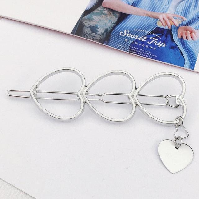 Silver heart-shaped hair clip with a heart charm on a white surface.