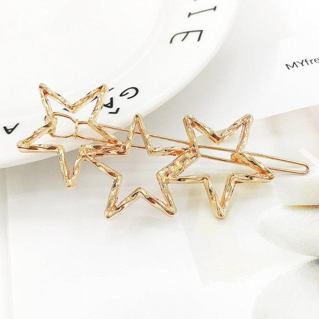 Gold star-shaped hair clips on a white surface