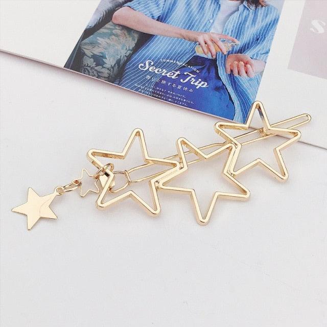 Gold star-shaped earrings on a white surface with a magazine in the background.