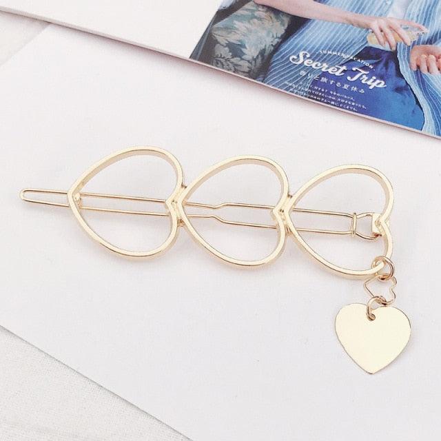 Gold hair clip with a heart charm on a light background