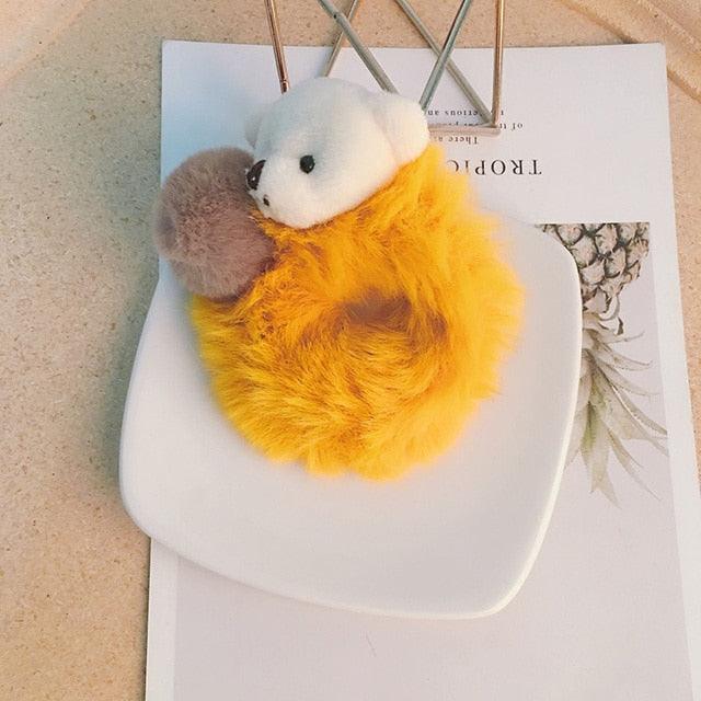 Plush toy shaped like a bear in a yellow pouch on a white surface with a magazine underneath.