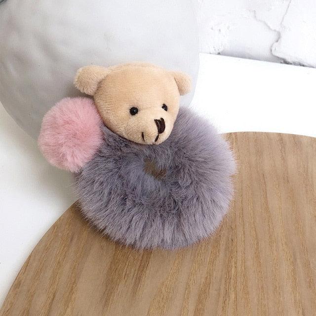 Teddy bear with fluffy gray and pink ears on a wooden surface