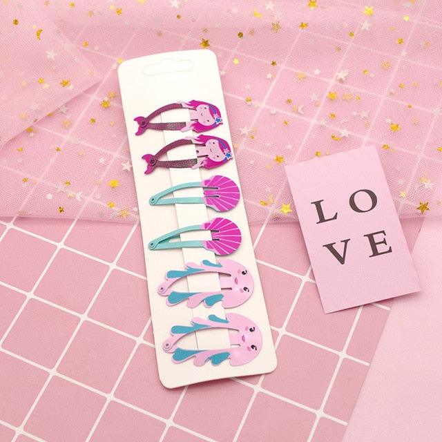 Set of colorful hair clips on a pink grid background with 'LOVE' card.