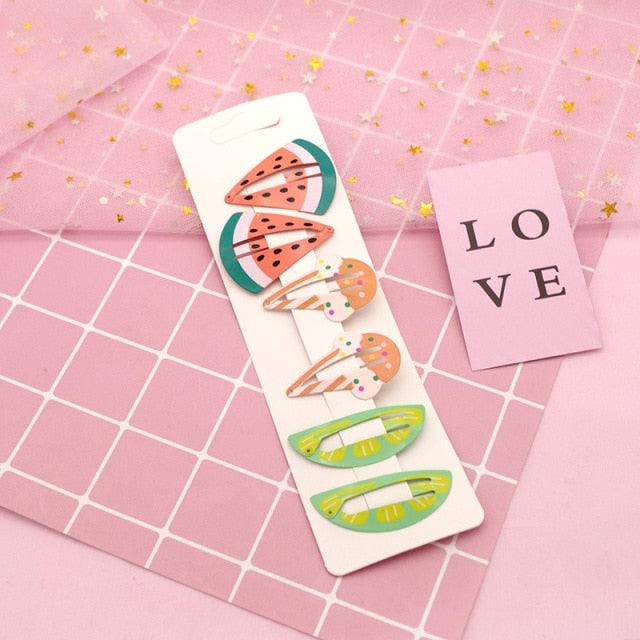 Set of colorful hair clips on a pink grid background with 'LOVE' card
