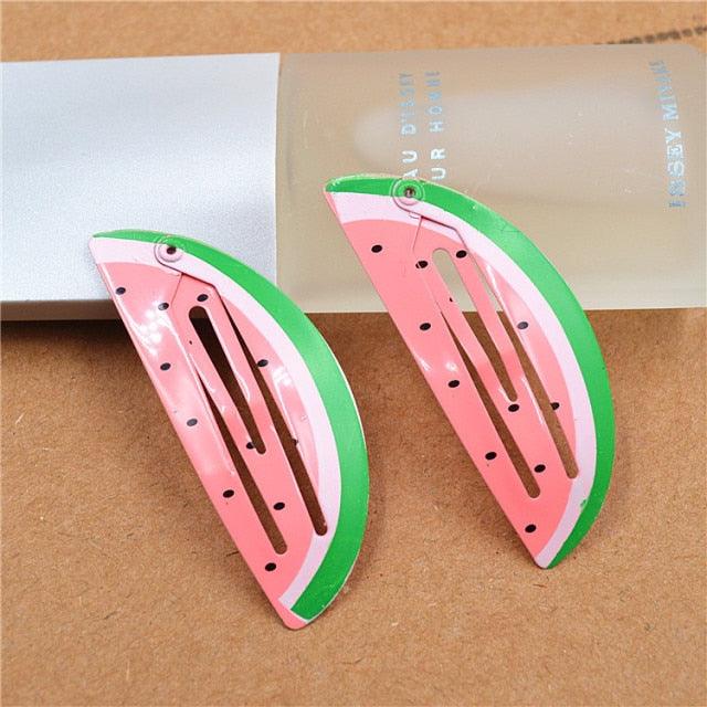 Watermelon-themed hair clips on a brown surface
