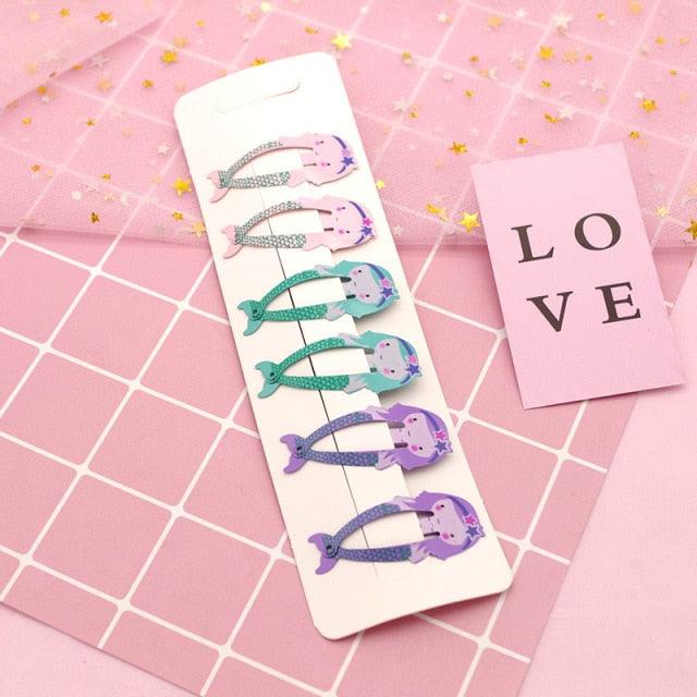 Set of colorful hair clips in a white packaging on a pink grid background with 'LOVE' card.