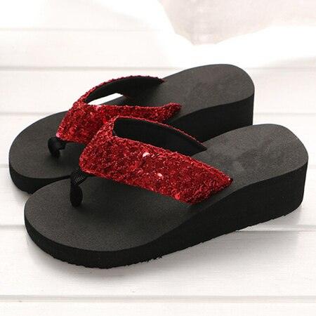 Black sandals with red glittery straps on a white background