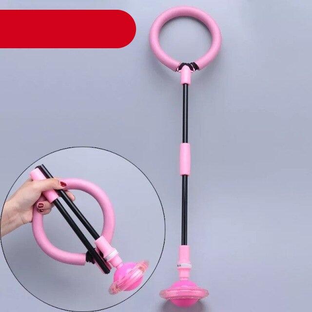 Pink and black exercise ring with a hand holding it on a gray background