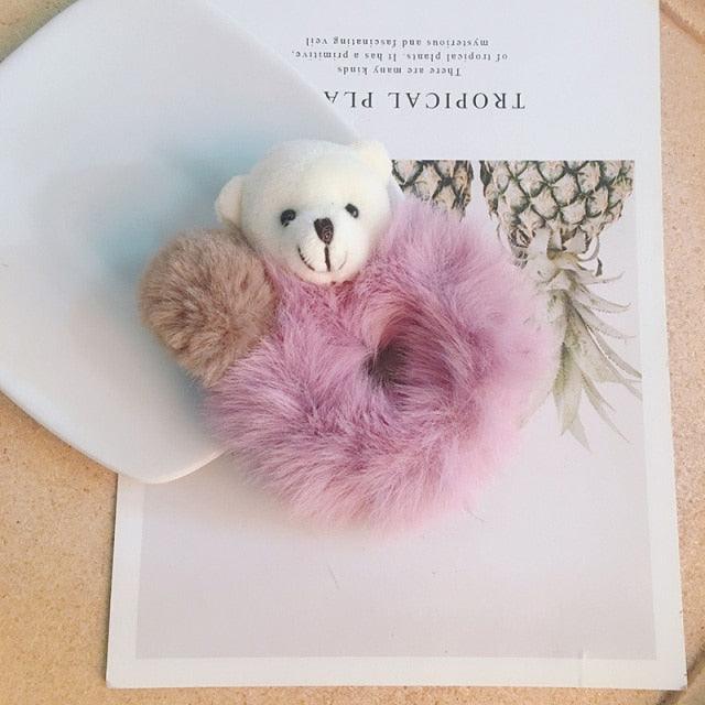 Small white teddy bear with a pink fluffy heart on a decorative card.