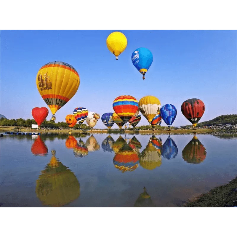 Colorful hot air balloons reflected in a calm body of water with a clear blue sky.