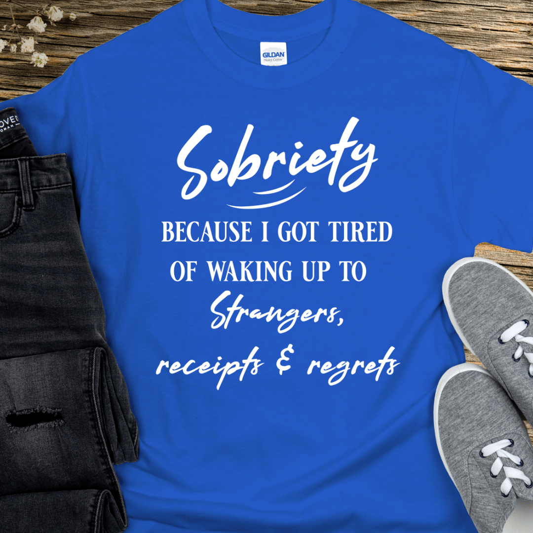 Blue t-shirt with motivational quote on a wooden surface with jeans and shoes.