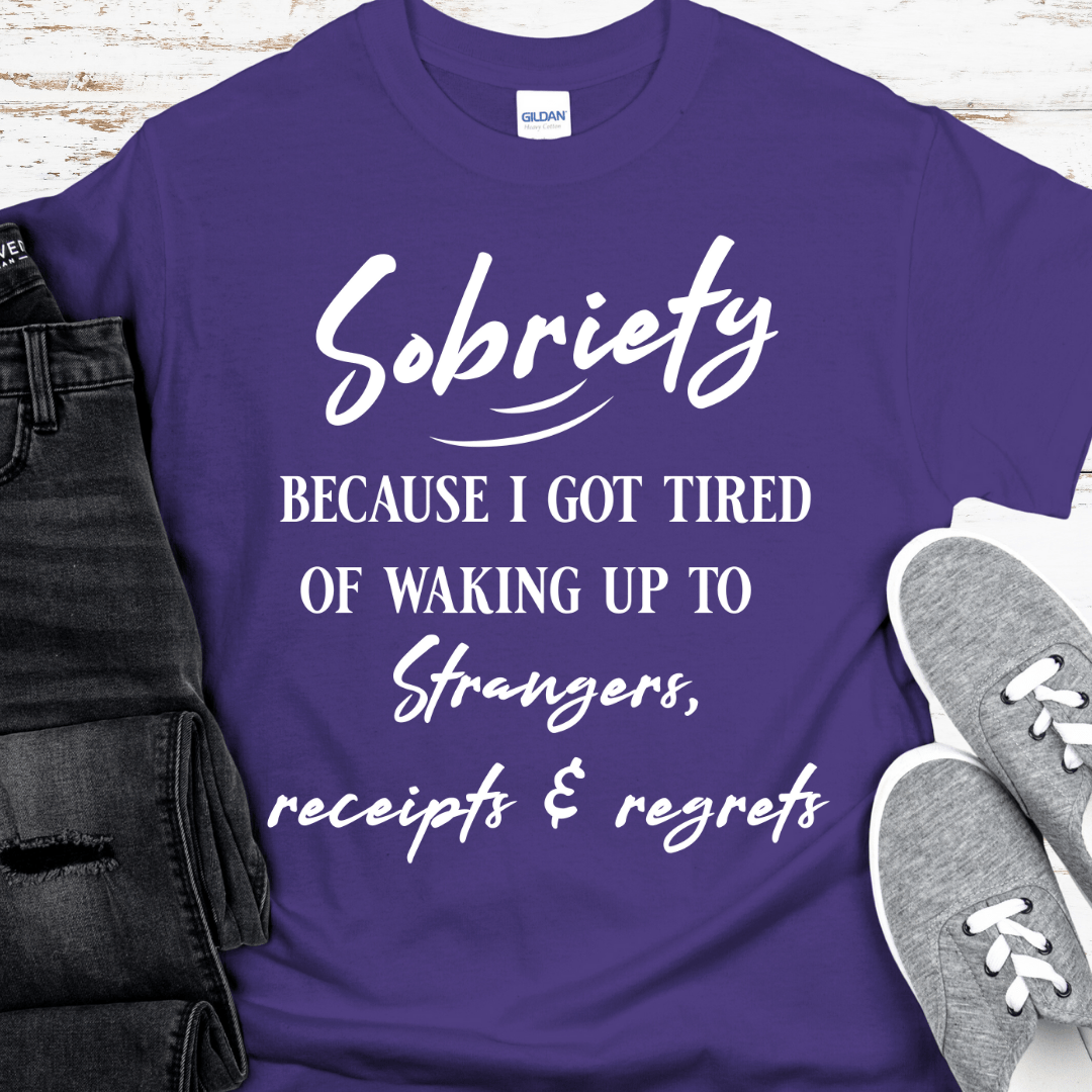 Purple t-shirt with motivational quote on a wooden surface with jeans and sneakers.
