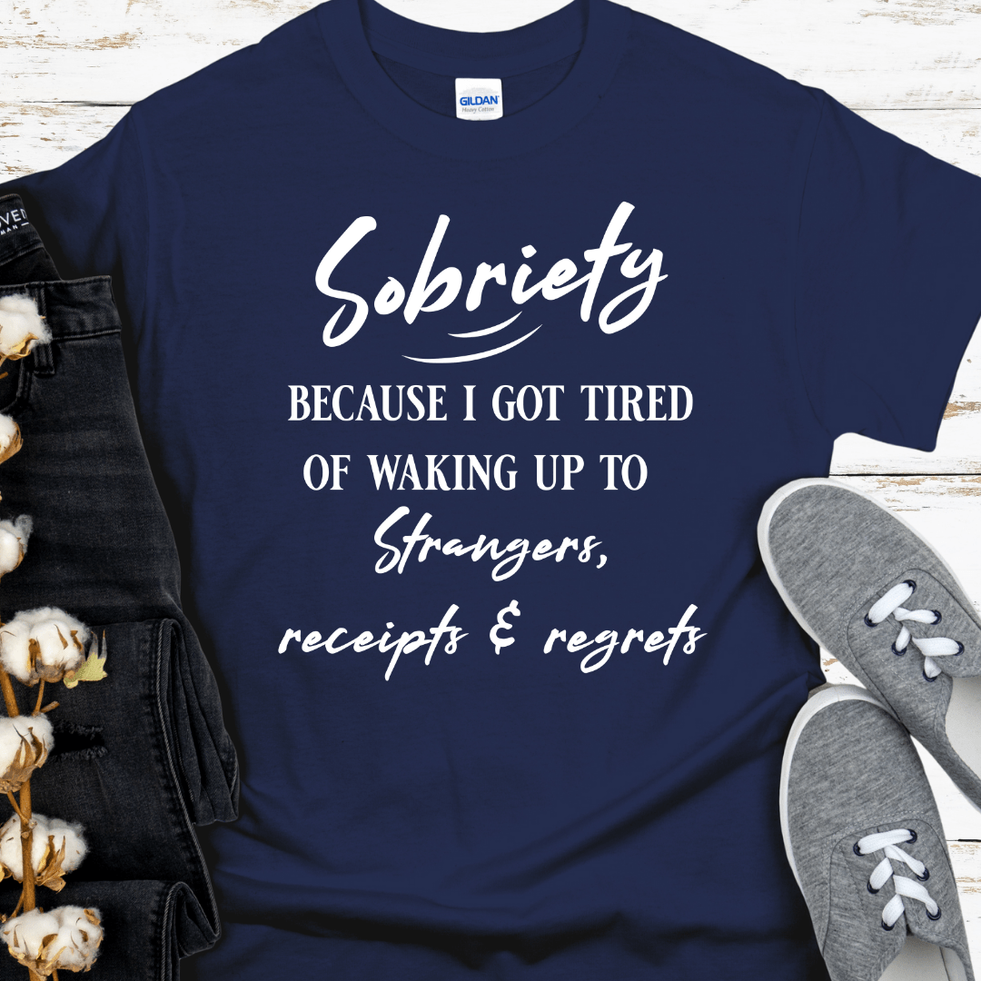 Navy blue t-shirt with white text on a wooden surface with shoes and cotton plant.