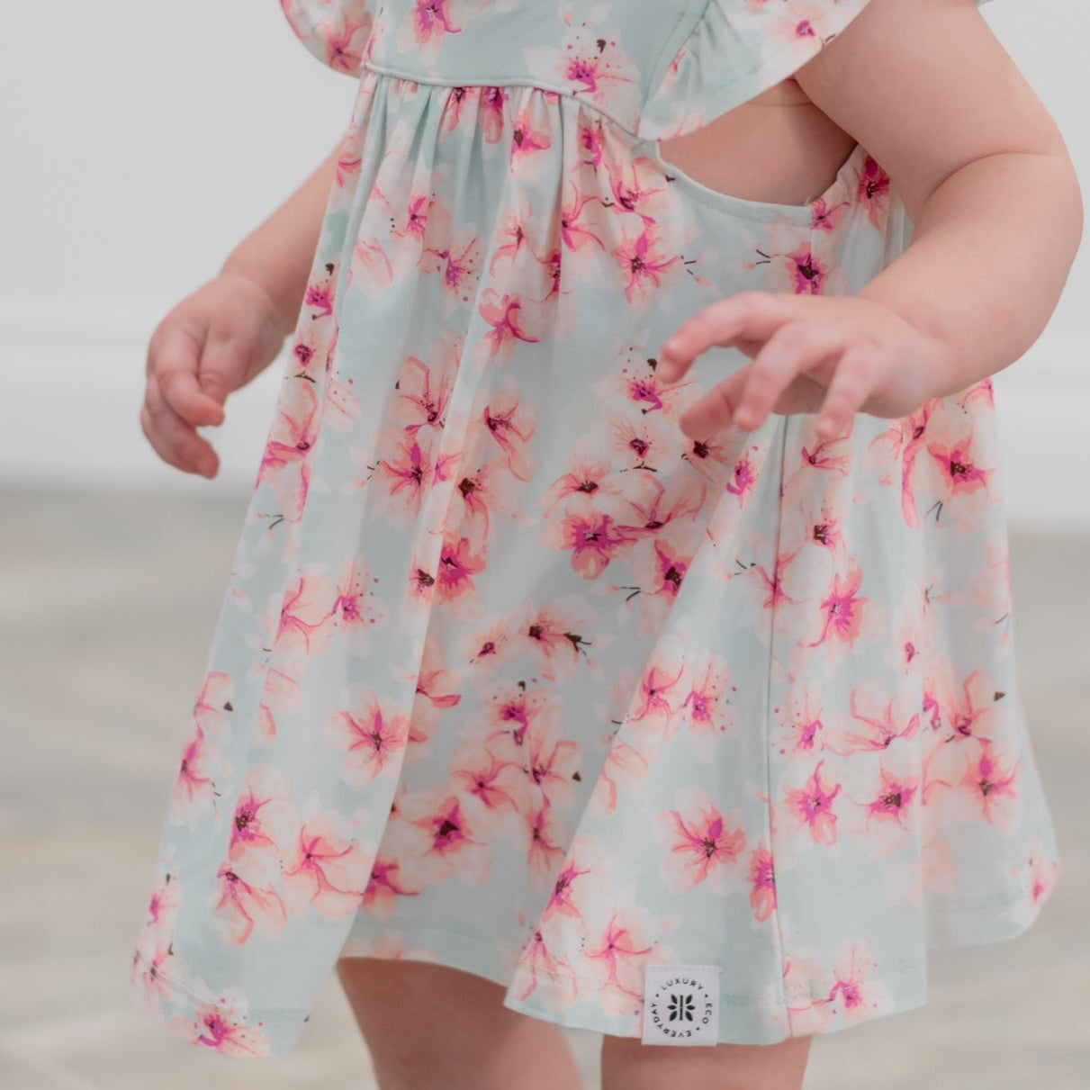 Child wearing a light blue floral dress on a beach.