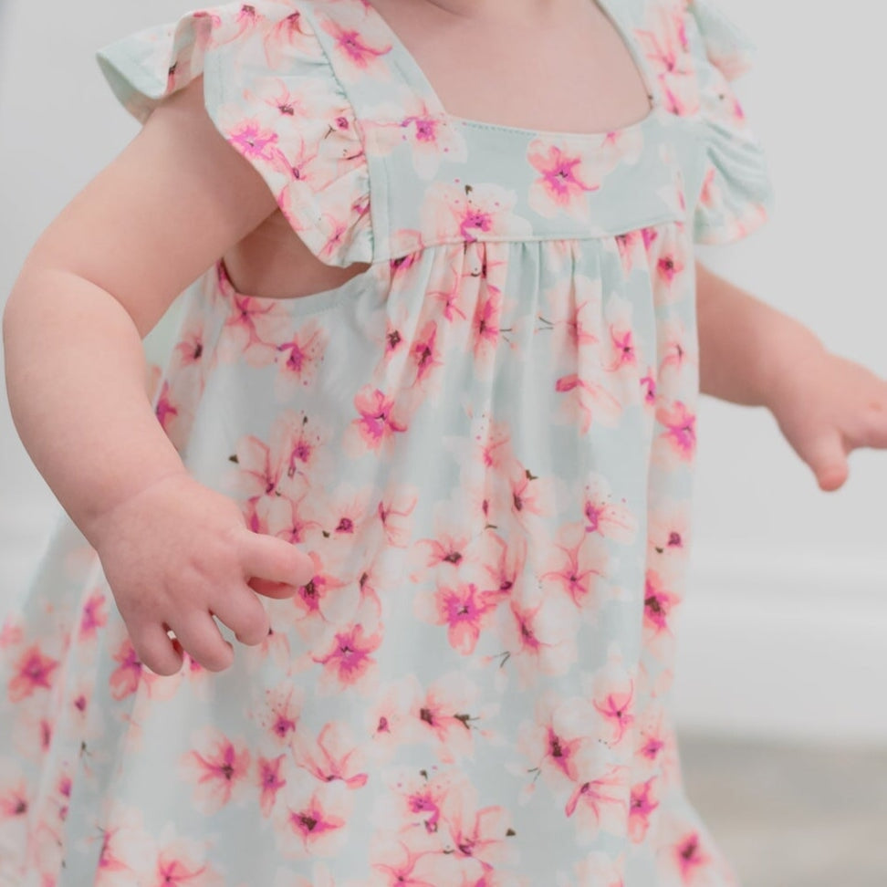 Child wearing a floral dress with pink flowers on a light blue background