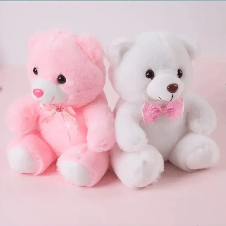 Two teddy bears, one pink and one white, sitting side by side on a pink background.