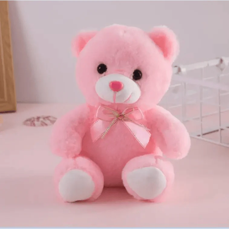 Pink teddy bear with a bow on a light pink background