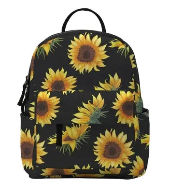 A black backpack featuring a vibrant yellow and brown sunflower print, shown against a plain white background.