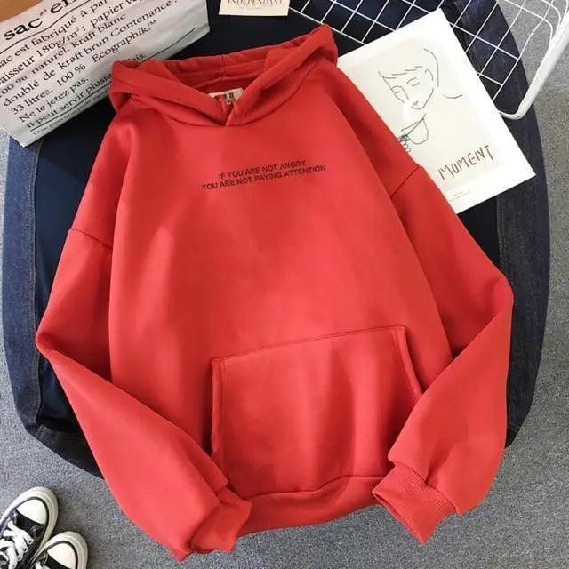 Red hoodie with text on a surface with books and shoes