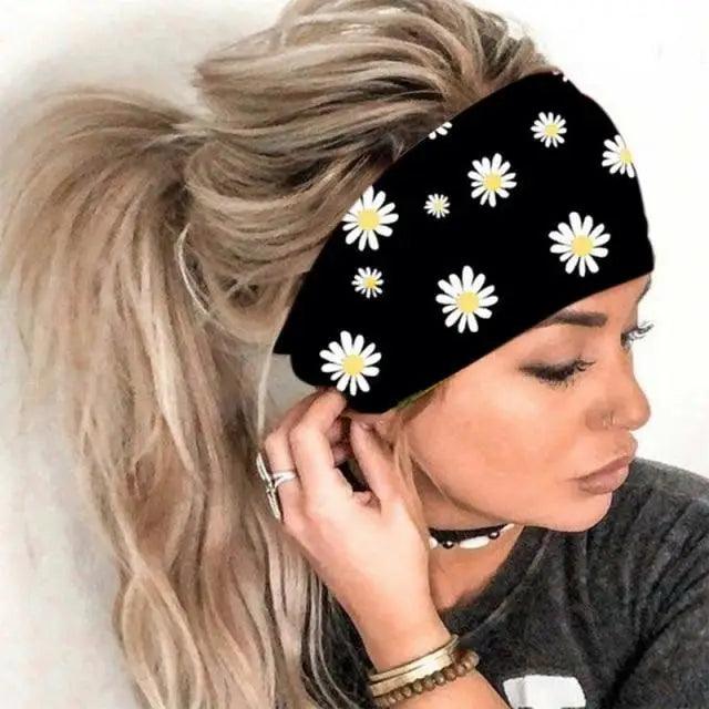 Woman wearing a black headband with white daisy patterns on a plain background