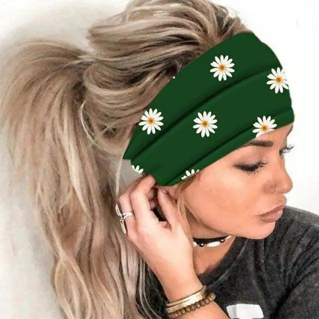 Green headband with white daisy patterns worn by a person with blonde hair.