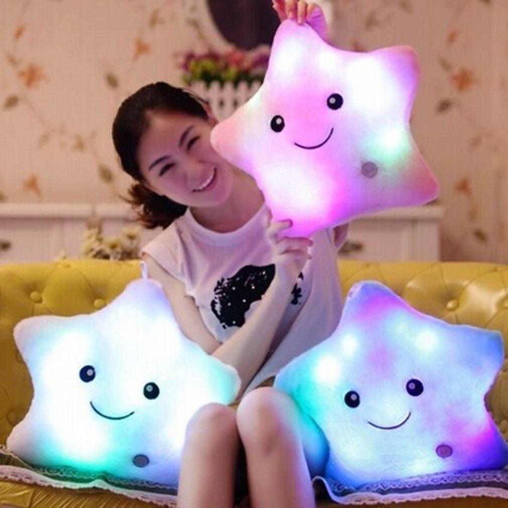 Person holding a glowing star-shaped pillow with a smiley face design.