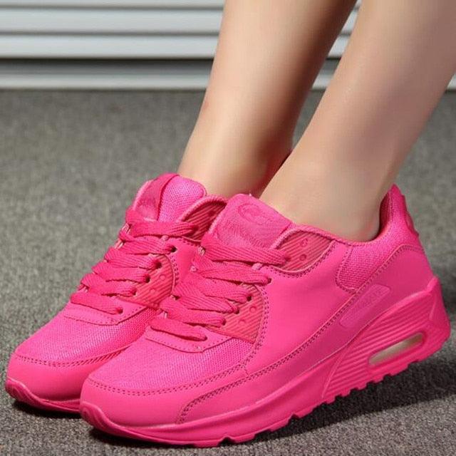 Pink sneakers worn on a neutral background