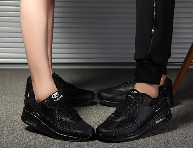 Black athletic shoes worn by a person on a neutral background